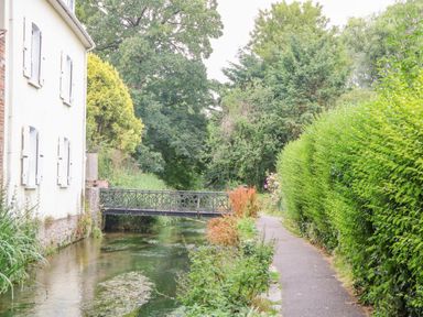 A narrow canal next to a paved pathway with a white building and a small bridge at The Town House in Dorchester