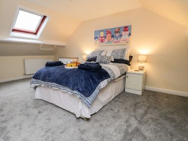 A bedroom with a double bed bedside tables a skylight window and a painting above the bed at Harbour Hideaway in Whitby