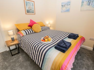 A bedroom with a double bed with striped bedding pillows and bedside lamps at Harbour Hideaway in Whitby
