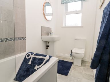 A bathroom with a bathtub a sink a toilet and blue mats at Harbour Hideaway in Whitby