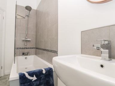 A bathroom with a bathtub and shower and a sink with a faucet at Harbour Hideaway in Whitby