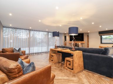 A living room with leather chairs and a blue sofa with lamps on a wooden table at Hare's Breath in Bowness-On-Windermere