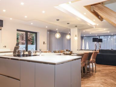 A kitchen island with cookware and knives next to a dining table with chairs in an open living space at Hares Breath in Bowness On Windermere