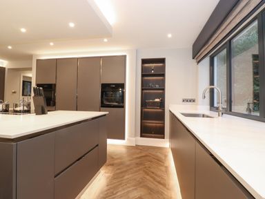 A kitchen with a large island knife block built in ovens and a sink under a window at Hares Breath in Bowness-On-Windermere