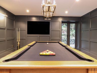 A billiard room with a pool table and balls in a rack a large screen on the wall and glass doors at Hares Breath Bowness-On-Windermere