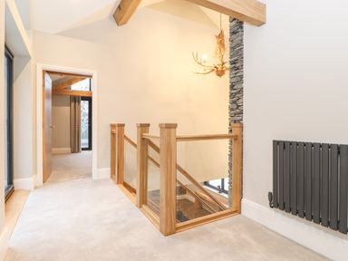 A hallway with carpeted floor wooden railing and an open door leading to another room at Hares Breath in Bowness-On-Windermere