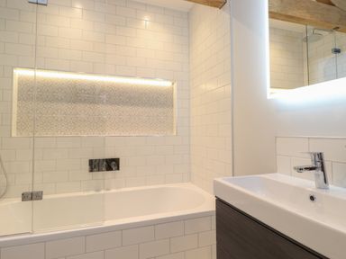 A bathroom with a bathtub sink and illuminated mirror at Hares Breath Bowness-On-Windermere