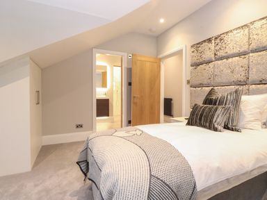 A bedroom with a bed near an open door showing a bathroom at Hares Breath in Bowness On Windermere