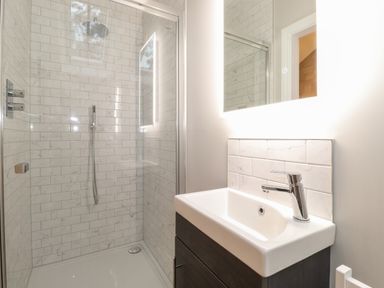 A bathroom with a tiled shower area and a sink with a mirror at Hares Breath in Bowness-On-Windermere
