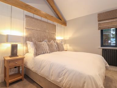 A bedroom with a bed pillows bedside tables lamps and a window at Hares Breath in Bowness-On-Windermere