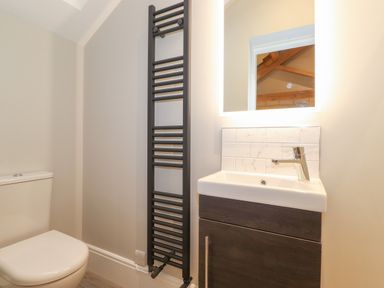 A bathroom with a toilet sink cabinet towel radiator and a mirror at Hares Breath Bowness-On-Windermere