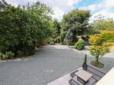 A gravel courtyard with a patio area and trees surrounding at Hares Breath in Bowness-On-Windermere