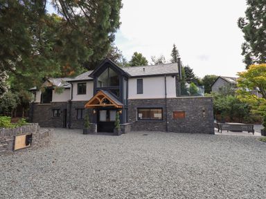 A two-story house with stone and white walls and a gravel driveway at Hares Breath in Bowness-On-Windermere