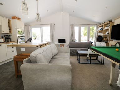A living room with sofas a pool table a coffee table and kitchen island at The Goodwood Lodge in Runcton near Chichester