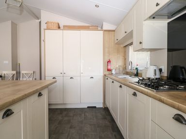 A kitchen with wooden countertops white cabinets gas stove and a sink at The Goodwood Lodge in Runcton near Chichester