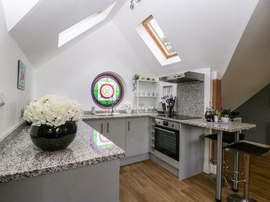 A kitchen with granite countertops a stained glass window and two bar stools at The Coach House in Ludlow