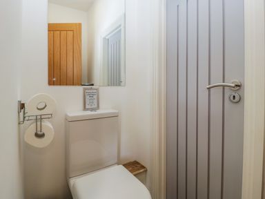 A toilet with a mirror and toilet paper holder in a small bathroom at The Coach House in Ludlow
