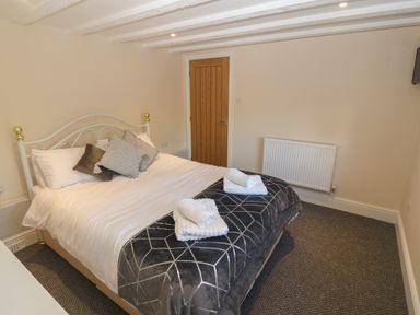 A bedroom with a double bed towels on the bed and a wooden door at Plas Eithin in Mynydd Mechell near Llanfechell