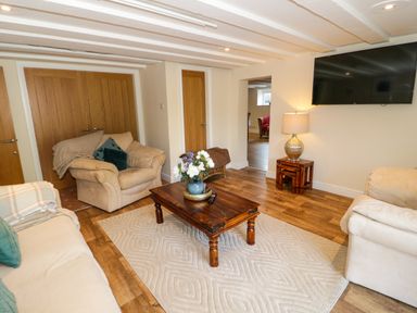 A living room with sofas a wooden coffee table and a wall mounted tv at Plas Eithin in Mynydd Mechell near Llanfechell