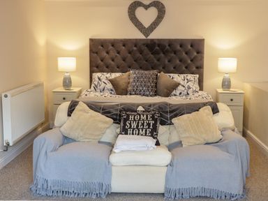 A bedroom with a bed sofa nightstands and lamps at Plas Eithin in Mynydd Mechell near Llanfechell