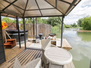 An outdoor area with a hot tub and seating at Oak Lodge At Bridge Lake Farm & Fishery Chacombe