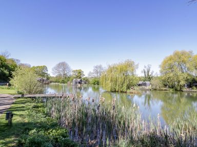 A pond with fishing huts at Oak Lodge At Bridge Lake Farm & Fishery in Chacombe
