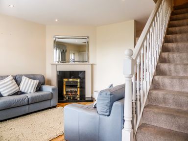 A living room with two blue sofas near a fireplace and a carpet adjacent to a staircase at Beach View in Duncannon near Ramsgrange County Wexford