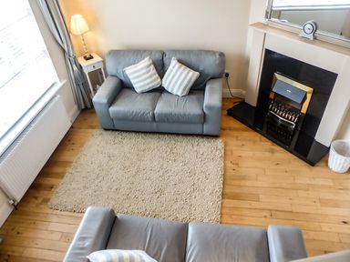 A living room with two sofas striped cushions a lamp a fireplace and a rug at Beach View Duncannon near Ramsgrange County Wexford