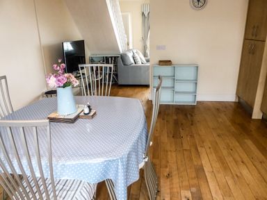 A dining area with a polka dot tablecloth on a round table and metal chairs and a living room with a sofa and television at Beach View in Duncannon near Ramsgrange County Wexford