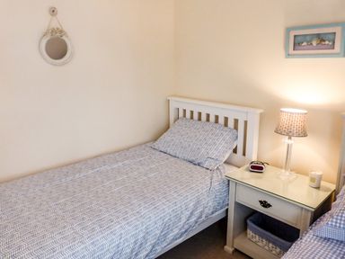 A bedroom with a single bed and nightstand with a lamp alarm clock and candle at Beach View in Duncannon near Ramsgrange County Wexford
