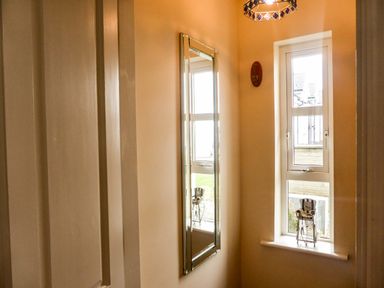 A narrow hallway with a rectangular wall mirror and a window with a decorative item on the sill at Beach View in Duncannon near Ramsgrange County Wexford