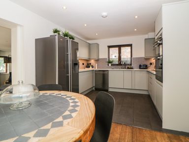 A kitchen with a round wooden table and chairs a double refrigerator and built in oven at Iroko in Millbrook