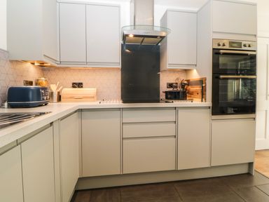 A kitchen with white cabinets a countertop stove a blue toaster and a double oven at Iroko in Millbrook
