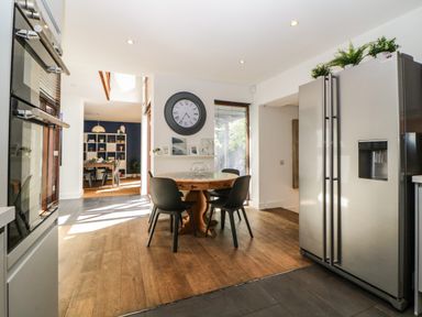 A kitchen with a round wooden table and four chairs next to a double-door refrigerator at Iroko in Millbrook