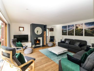 A living room with a fireplace a television several chairs a white coffee table and landscape pictures on the wall at Iroko in Millbrook