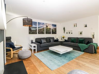 A living room with two gray sofas green cushions a white coffee table and wall art at Iroko in Millbrook