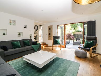 A living room with sofas green cushions a white coffee table a green rug and wooden flooring at Iroko Millbrook