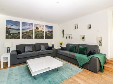 A living room with two grey sofas a white coffee table and a blue rug at Iroko in Millbrook