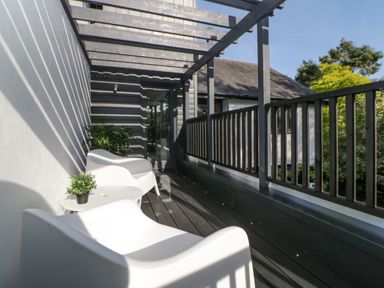 A balcony with two white chairs a small table with a plant and wooden railing at Iroko in Millbrook