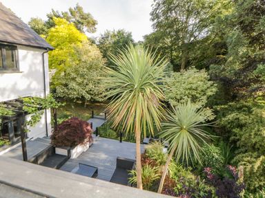 A garden patio with outdoor furniture and various trees and plants at Iroko in Millbrook