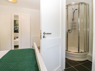 A bedroom with a green bedspread a white wardrobe and an en suite shower at Iroko in Millbrook
