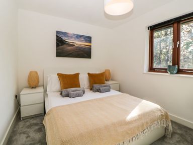 A bedroom with a bed having two brown pillows and two rolled towels with a painting above the bed at Iroko in Millbrook
