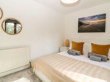 A bedroom with a bed covered by a blanket and cushions next to a bedside table with a lamp and two round mirrors on the wall at Iroko in Millbrook