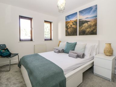 A bedroom with a bed with pillows and towels two windows and a chair at Iroko Millbrook