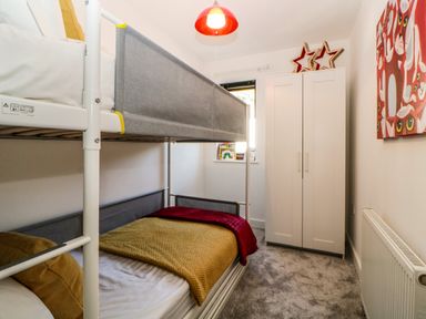 A bedroom with a bunk bed a white wardrobe a window and a heating radiator at Iroko in Millbrook