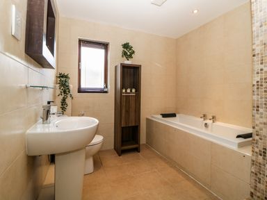 A bathroom with a sink toilet bathtub and a wooden cabinet at Iroko in Millbrook