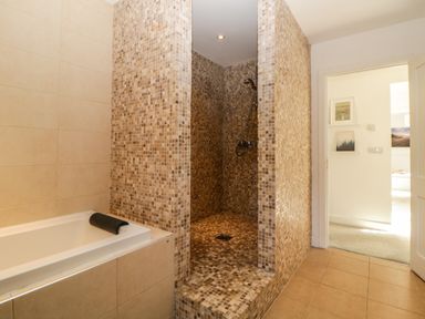 A bathroom with a tiled walk in shower and a bathtub at Iroko in Millbrook