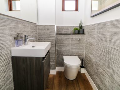A small bathroom with a white toilet and a sink with a cabinet and plants on a shelf at Iroko in Millbrook