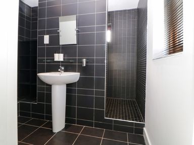 A bathroom with a pedestal sink a mirror tiled walls a walk in shower and a window with blinds at Iroko in Millbrook
