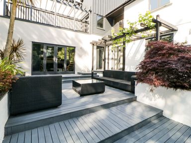 An outdoor patio area with black wicker furniture and a wooden pergola at Iroko in Millbrook